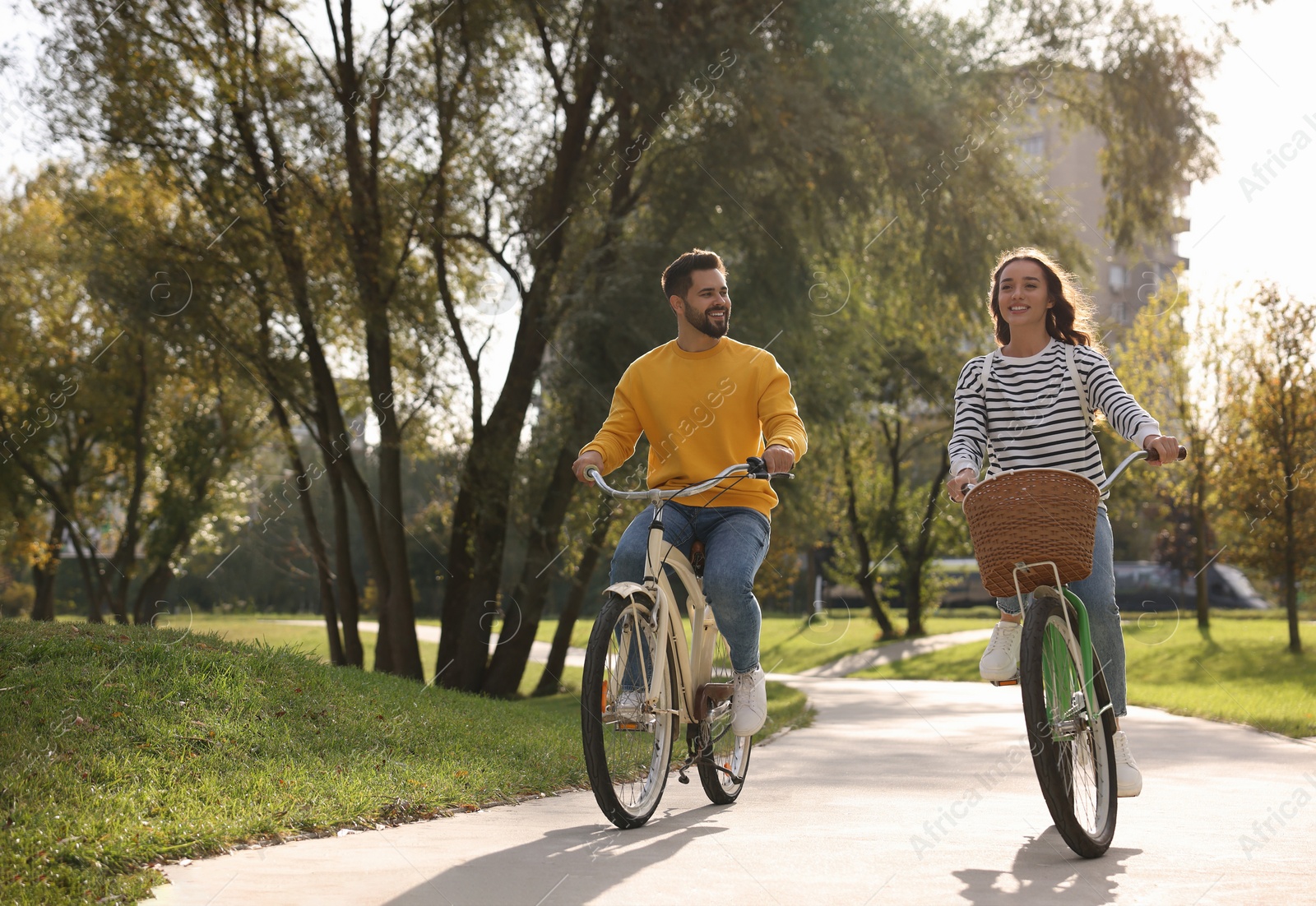 Photo of Beautiful couple riding bicycles in park, space for text