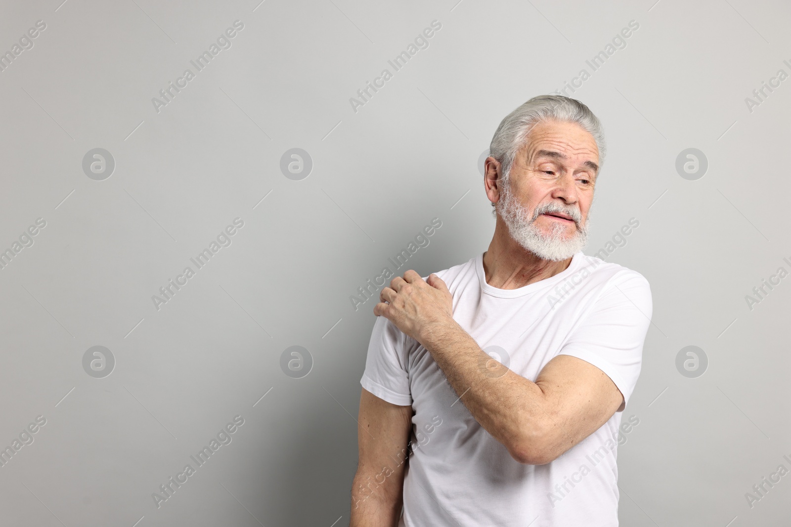 Photo of Arthritis symptoms. Man suffering from pain in shoulder on gray background, space for text