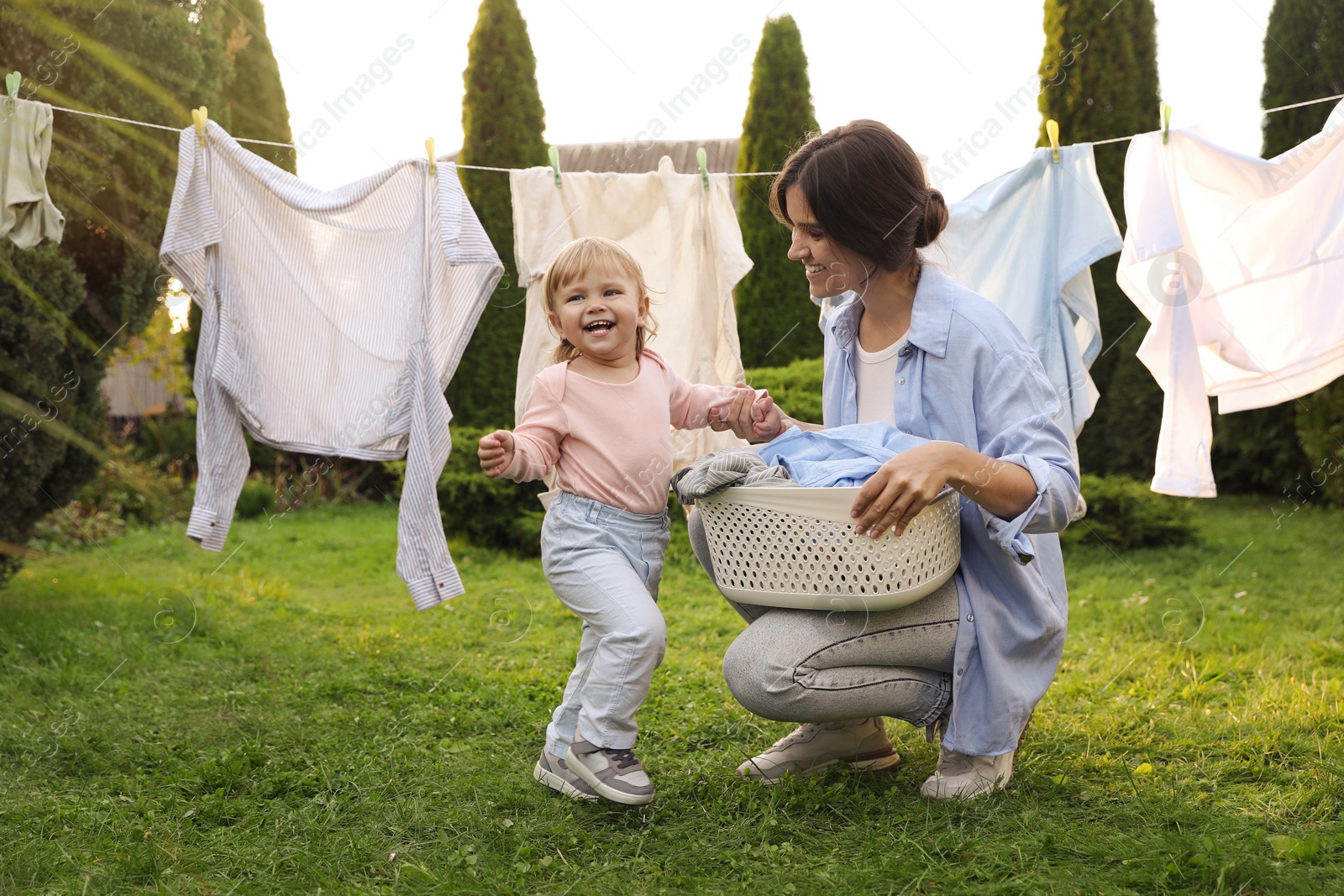 Photo of Mother and daughter near washing line with drying clothes in backyard