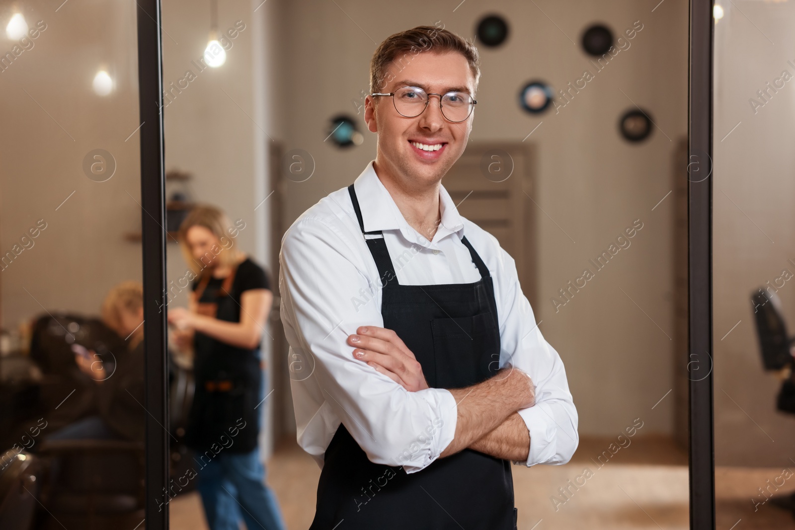 Photo of Portrait of professional hairdresser wearing apron in beauty salon