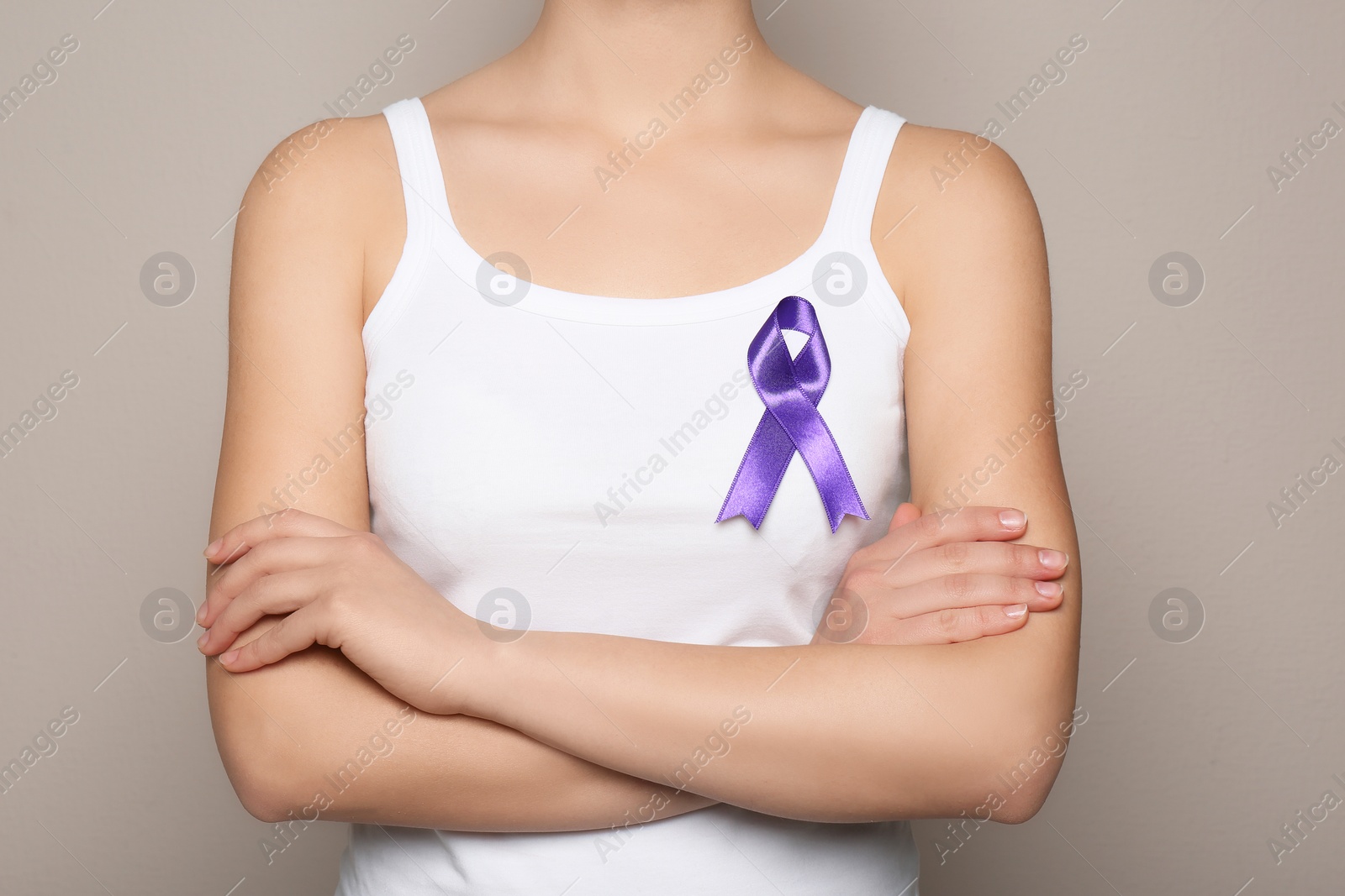 Photo of Woman wearing purple ribbon on grey background, closeup. Domestic violence awareness