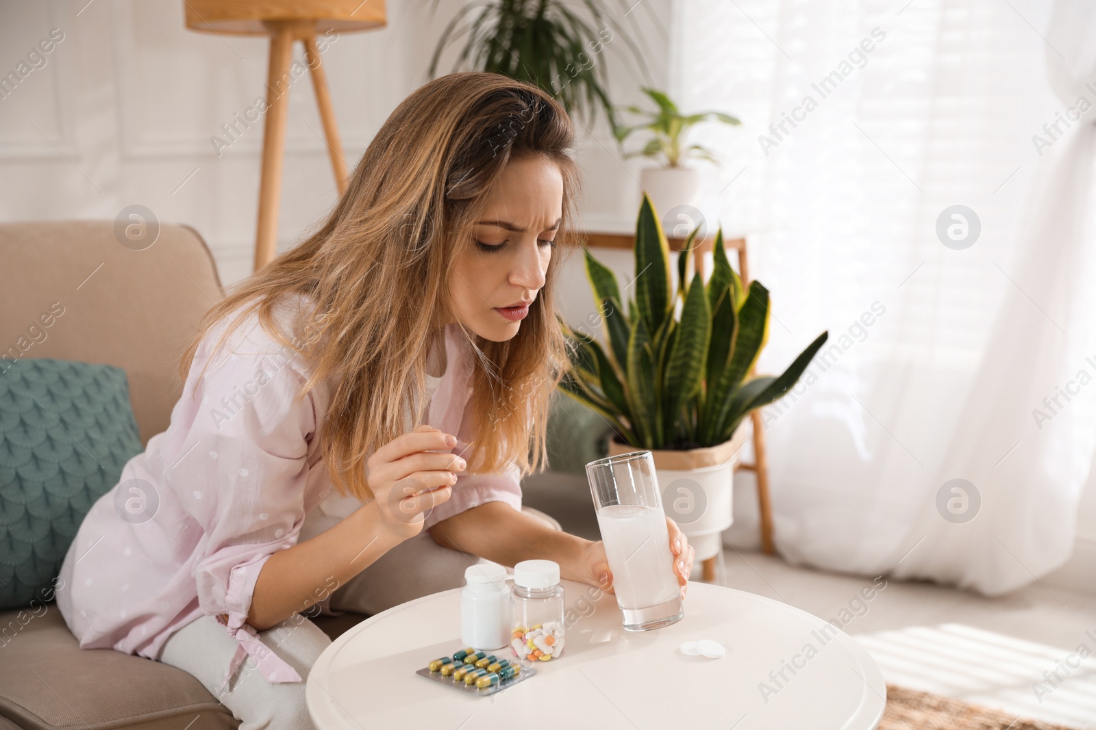 Photo of Woman holding glass of medicine for hangover at home