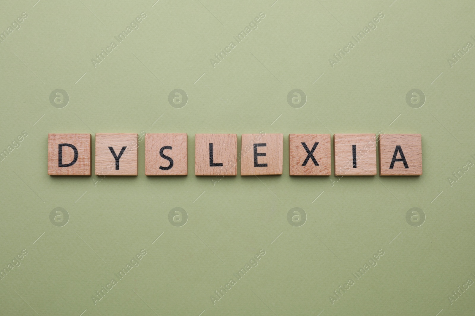 Photo of Wooden tiles with word Dyslexia on olive background, flat lay
