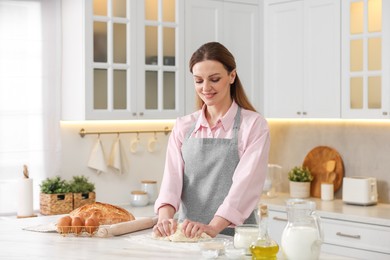 Making bread. Woman kneading dough at white table in kitchen