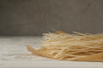 Photo of Raw rice noodles on wooden table, closeup. Space for text