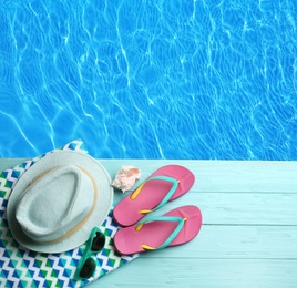 Beach accessories on turquoise wooden deck near swimming pool, flat lay 