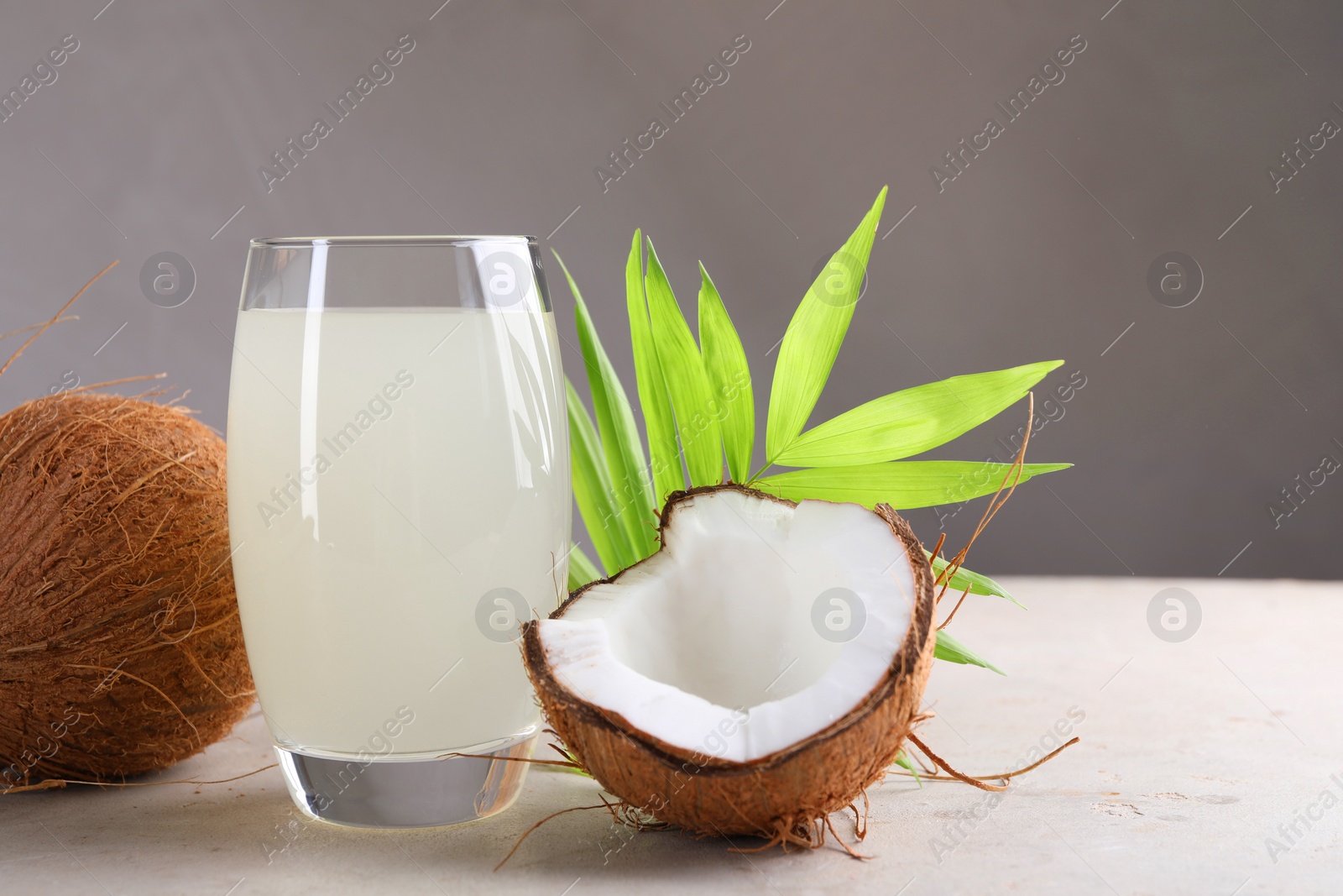 Photo of Glass of coconut water, palm leaves and nuts on light table