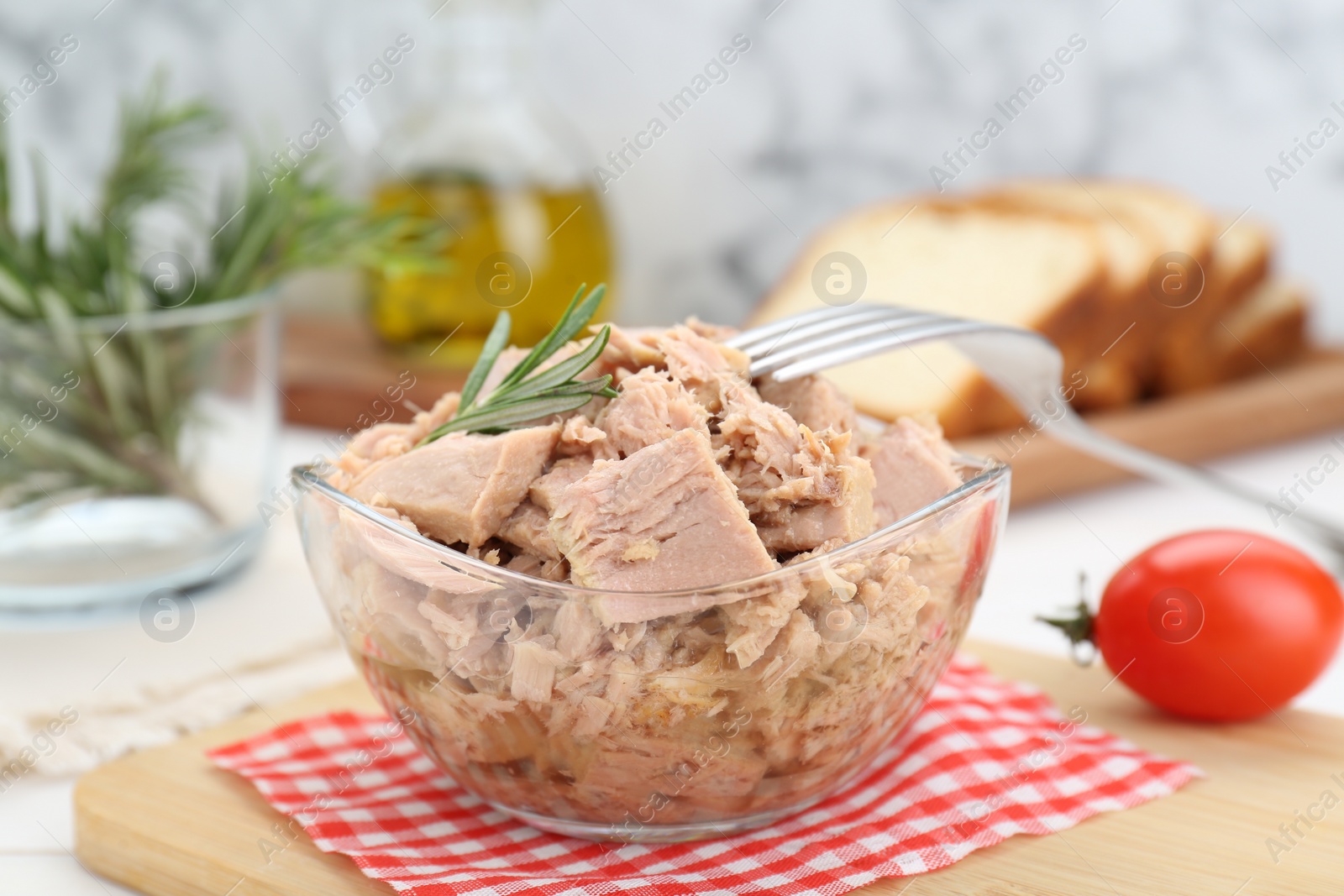 Photo of Bowl with canned tuna and rosemary on white table, closeup