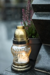 Grave light and potted heather on granite tombstone at cemetery