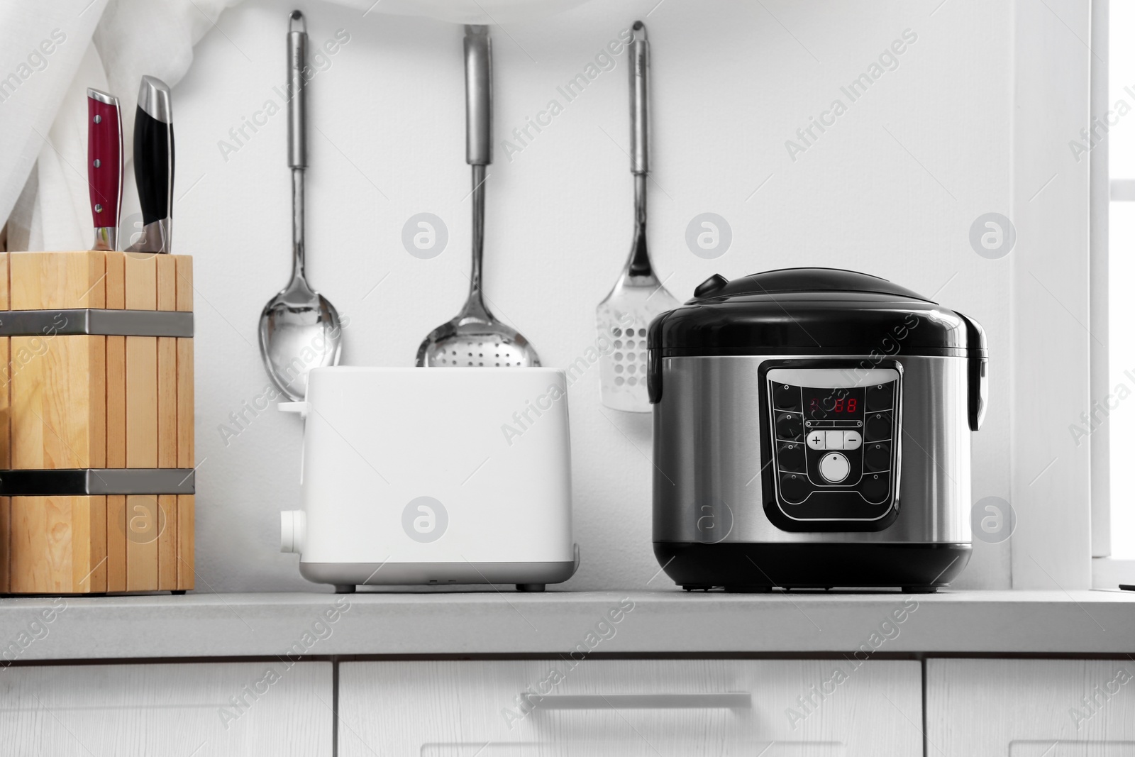 Photo of Modern electric multi cooker and toaster on kitchen countertop