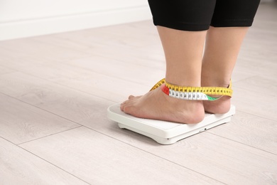 Photo of Overweight woman using scales indoors