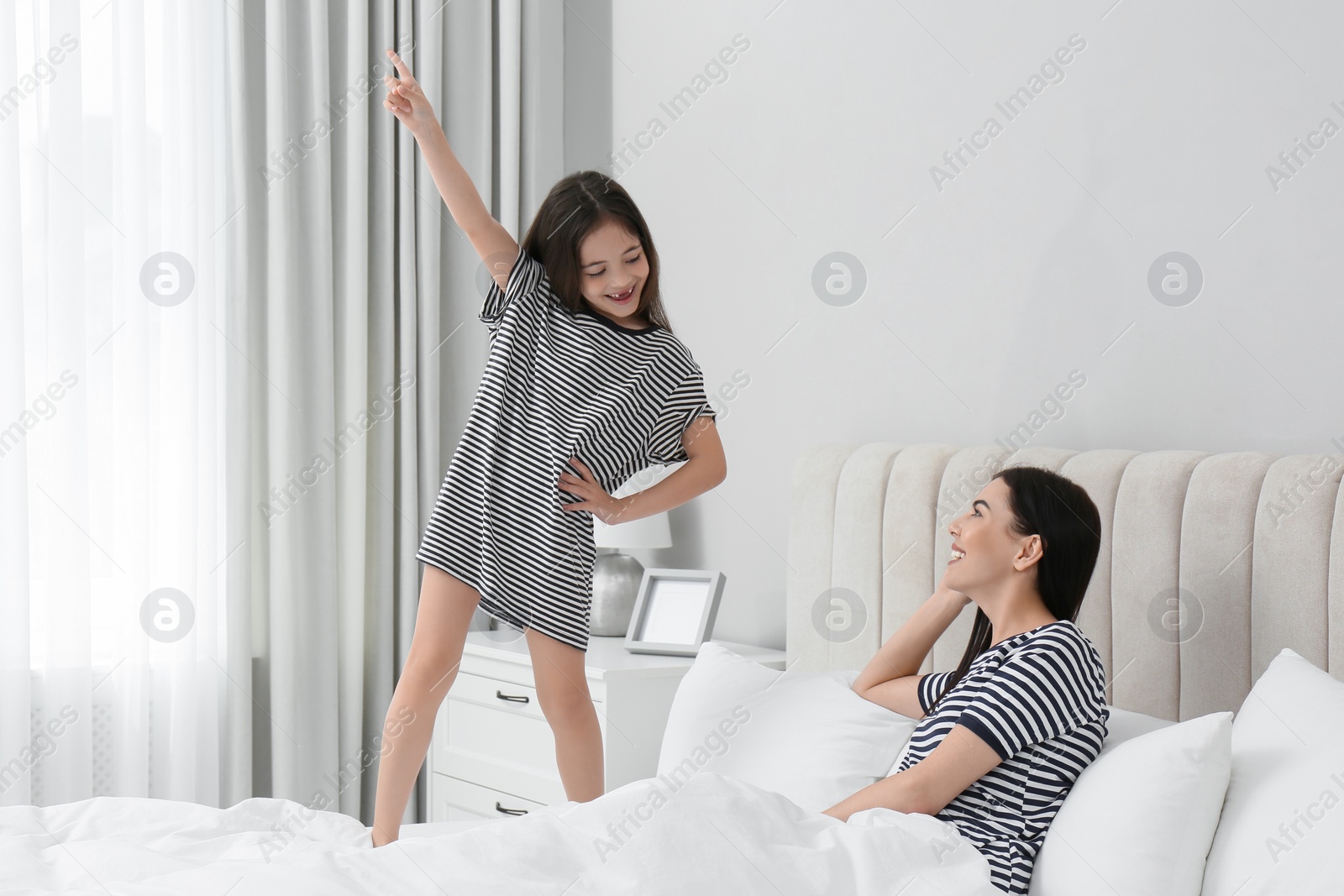 Photo of Young mother and her daughter having fun in bedroom