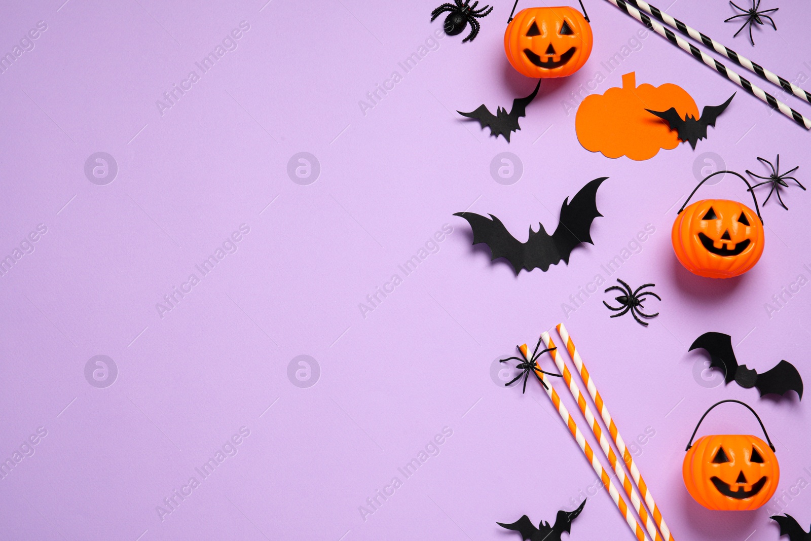 Photo of Flat lay composition with paper bats, spiders, plastic pumpkin baskets and cocktail straws on light violet background, space for text. Halloween decor