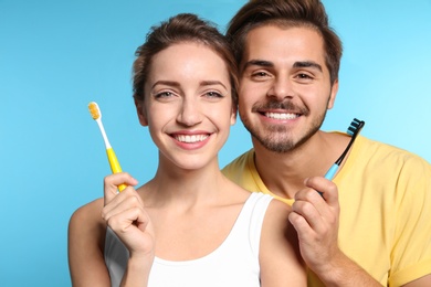 Portrait of young couple with toothbrushes on color background