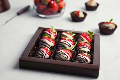 Box with chocolate covered strawberries on table