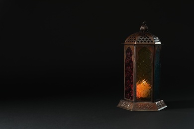 Photo of Muslim lamp with candle on black background. Fanous as Ramadan symbol