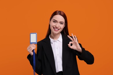 Happy woman with VIP pass badge showing OK gesture on orange background