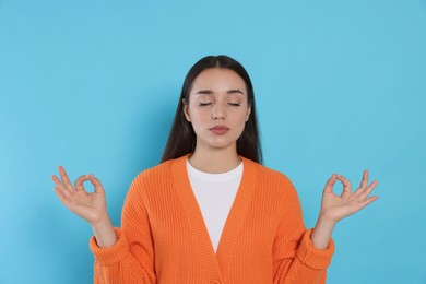 Photo of Find zen. Beautiful young woman meditating on light blue background