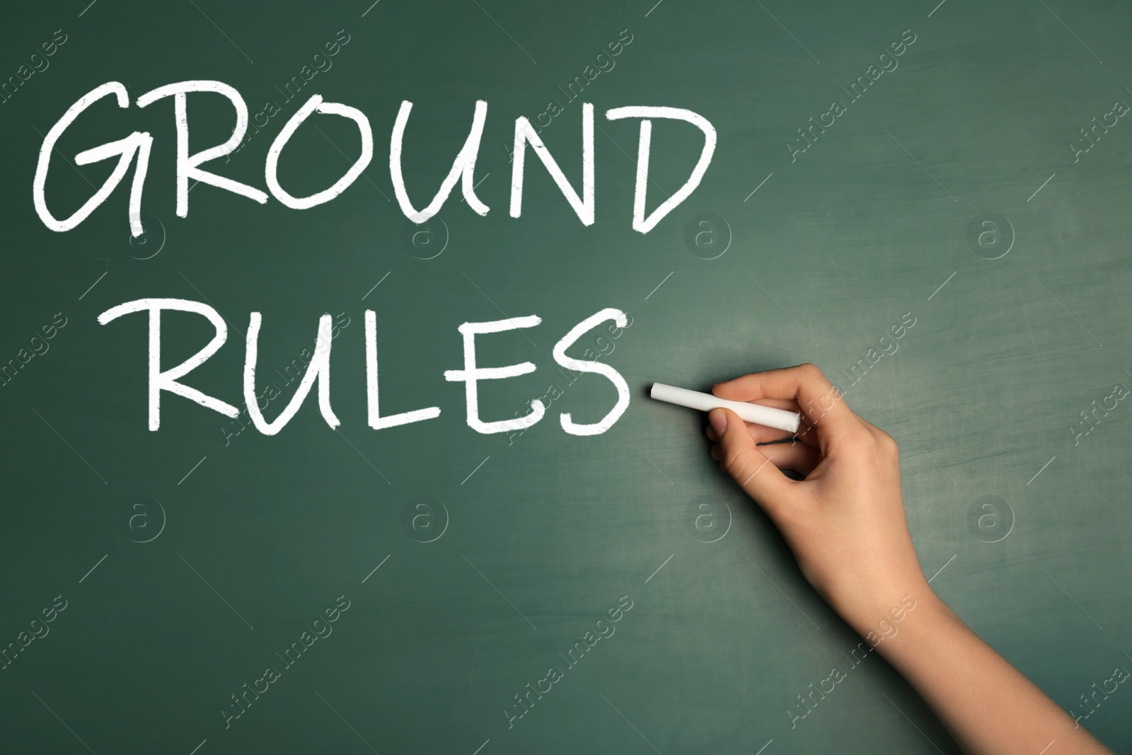 Image of Woman writing phrase GROUND RULES on chalkboard, closeup