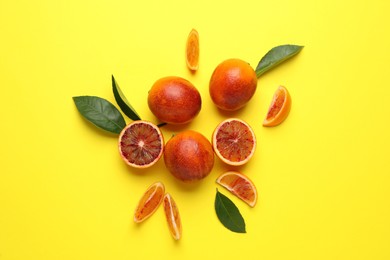 Photo of Many ripe sicilian oranges and leaves on yellow background, flat lay