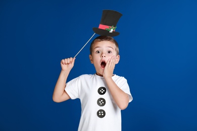 Shocked little boy with Christmas hat prop on blue background
