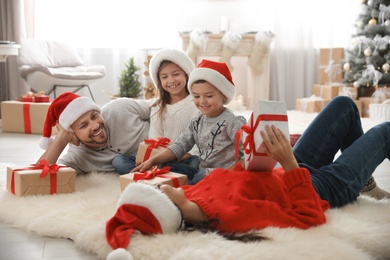 Photo of Happy family with Christmas gifts on floor at home