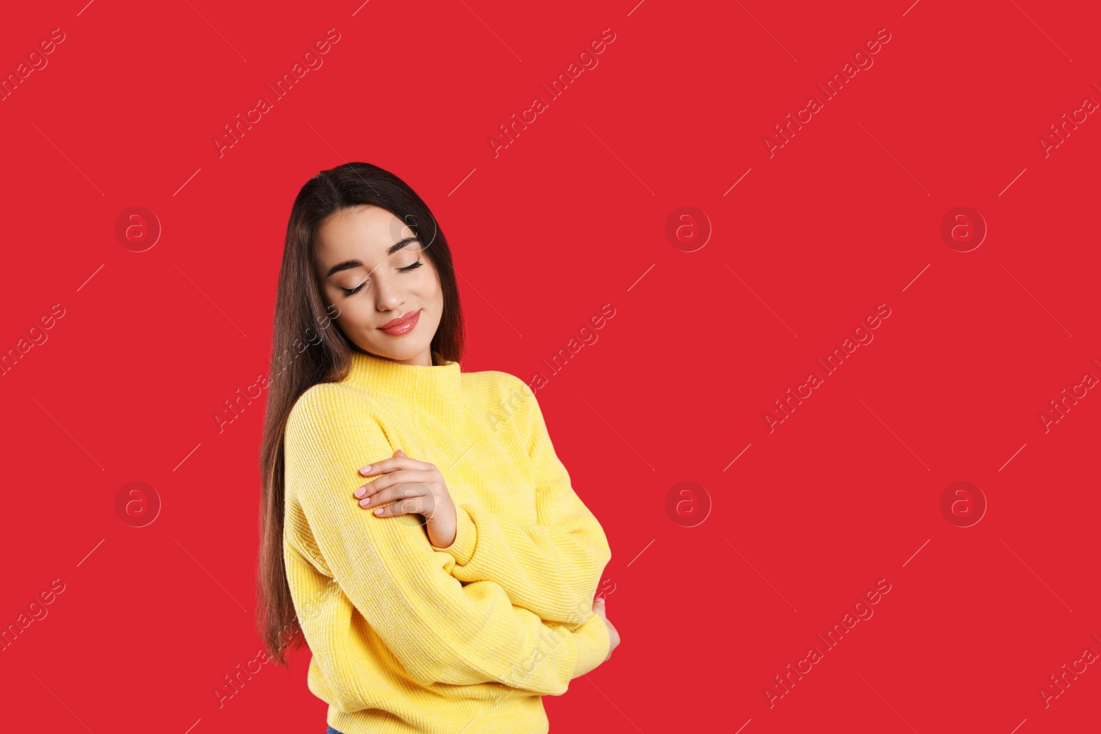 Photo of Beautiful young woman wearing yellow warm sweater on red background. Space for text