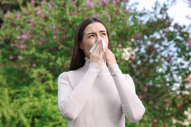 Woman with napkin suffering from seasonal allergy outdoors