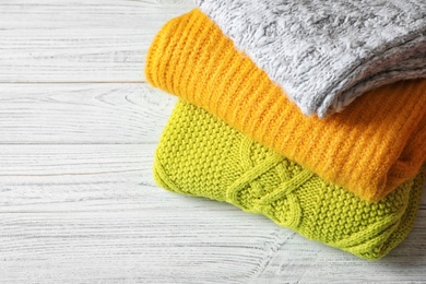 Photo of Stack of warm knitted clothes on wooden table