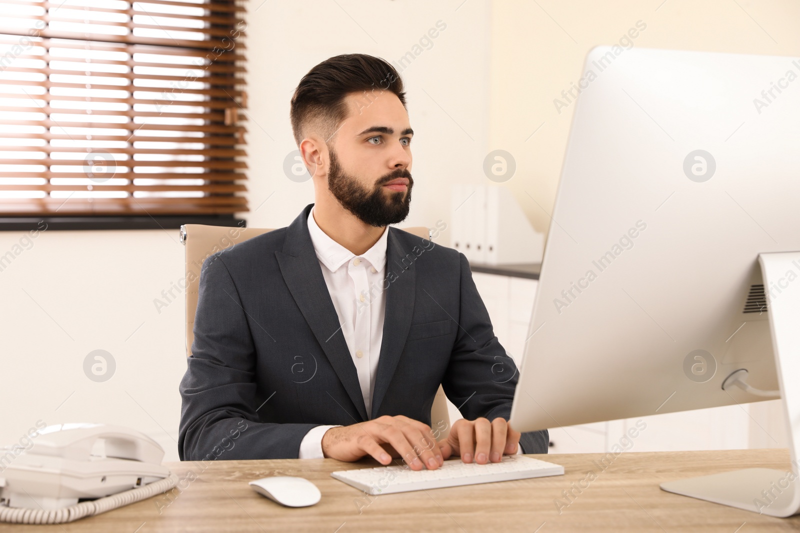 Photo of Handsome businessman working with computer at table in office