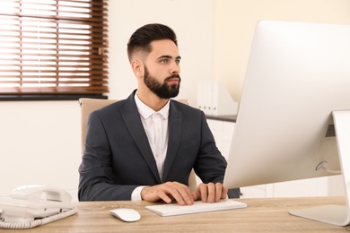 Handsome businessman working with computer at table in office