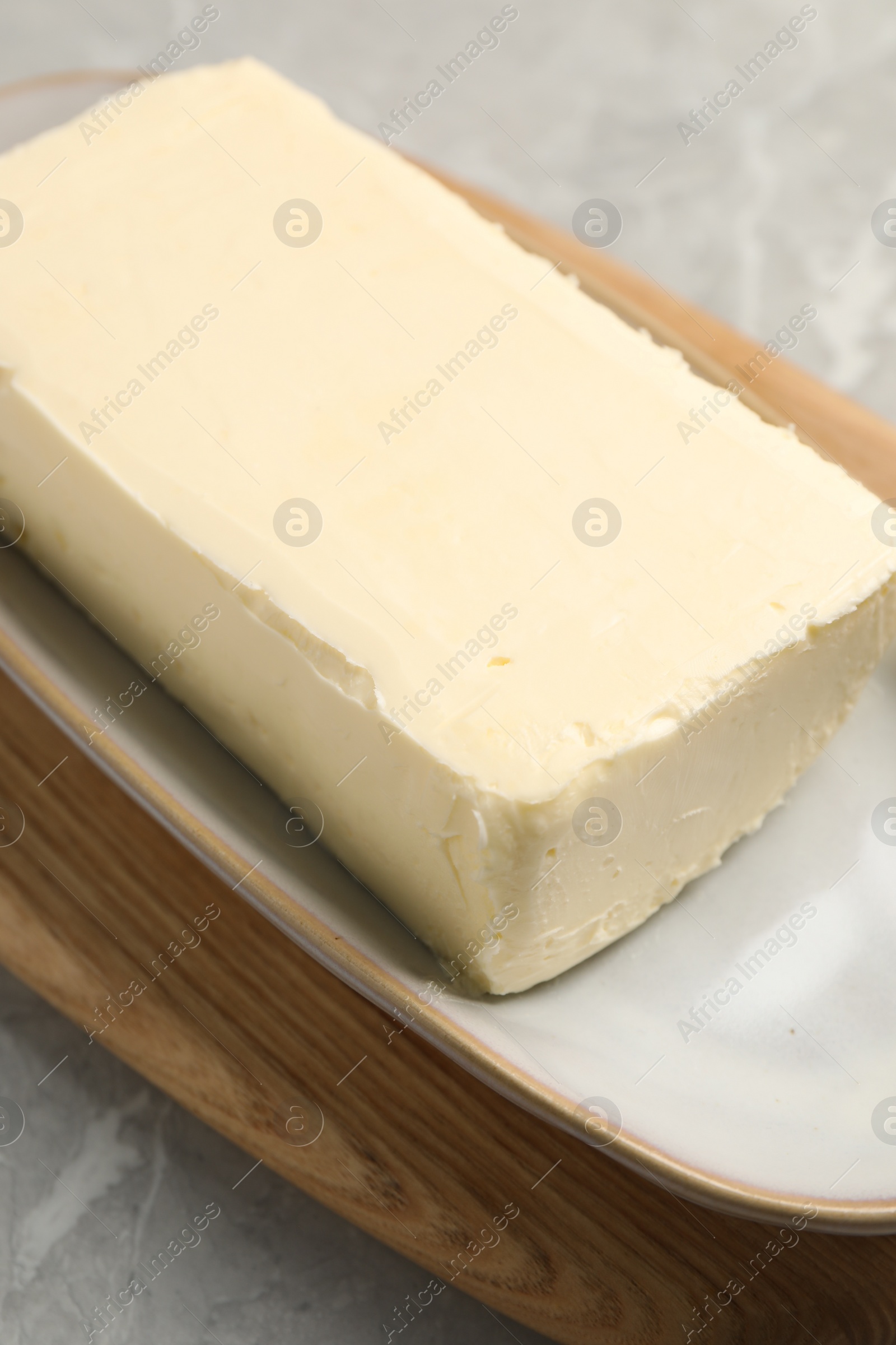 Photo of Block of tasty butter on grey table, closeup