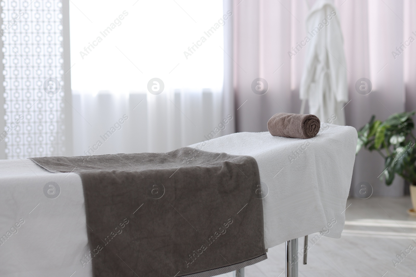 Photo of Comfortable massage table with clean towels in spa center