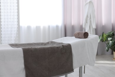 Comfortable massage table with clean towels in spa center