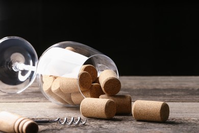 Photo of Glass with wine corks and corkscrew on wooden table