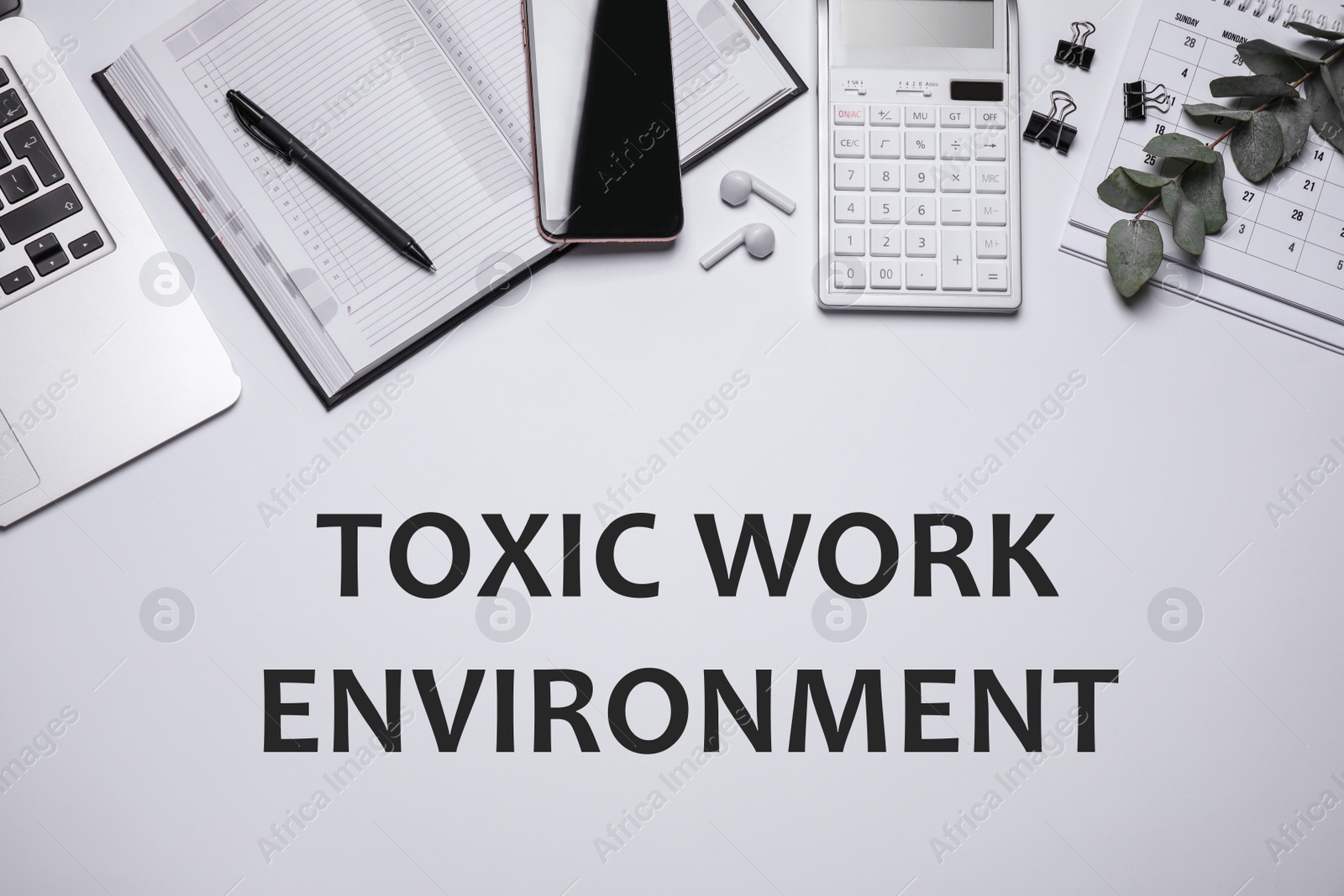 Image of Laptop, smartphone, stationery and text TOXIC WORK ENVIRONMENT on white background, flat lay. Space for text