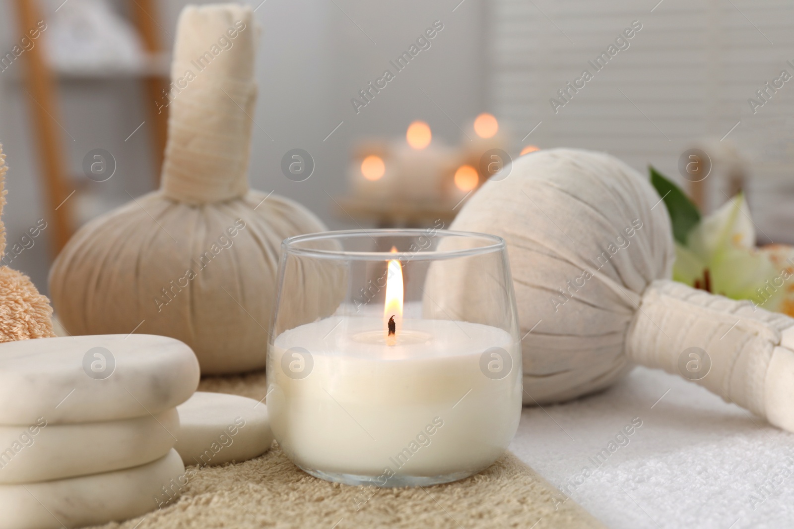 Photo of Spa composition with burning candle and herbal bags on massage table in wellness center