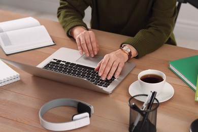 Photo of Woman with modern laptop learning at table indoors, closeup