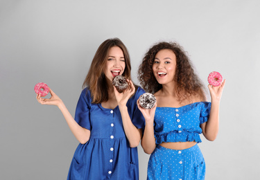 Photo of Beautiful young women with donuts on light grey background