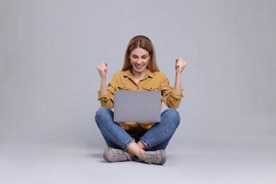 Photo of Emotional woman with laptop on light grey background