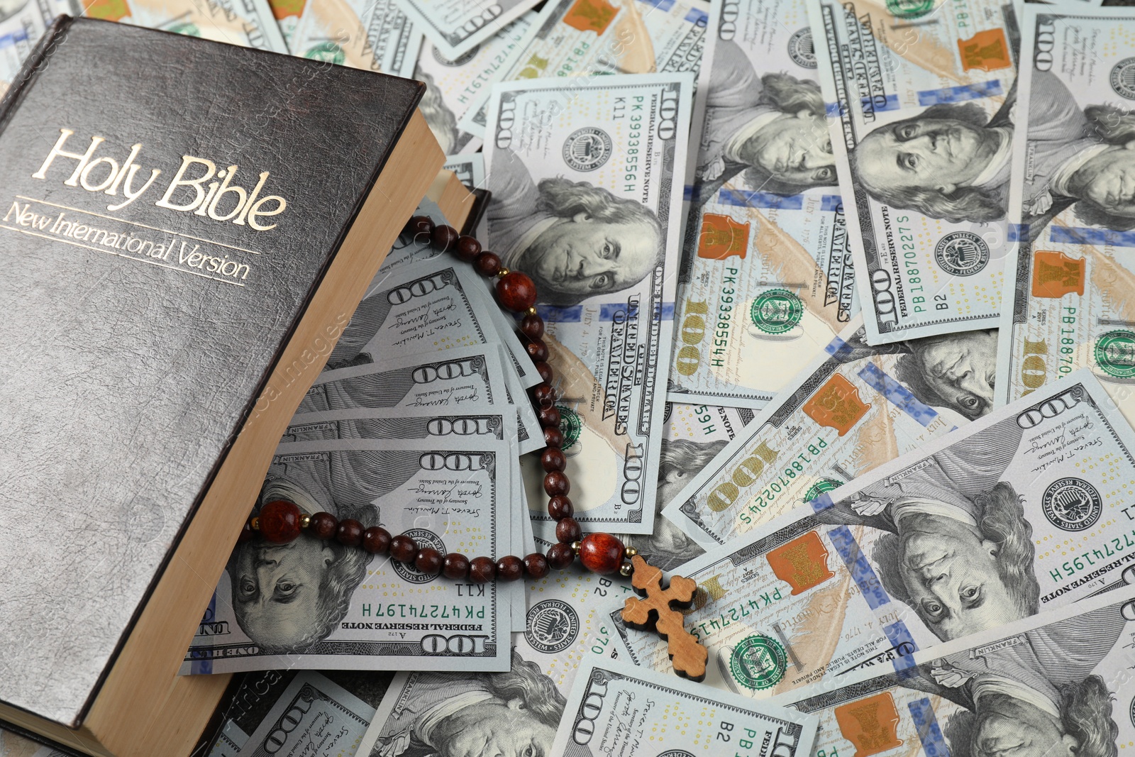 Photo of Holy Bible and wooden cross on dollar banknotes, closeup