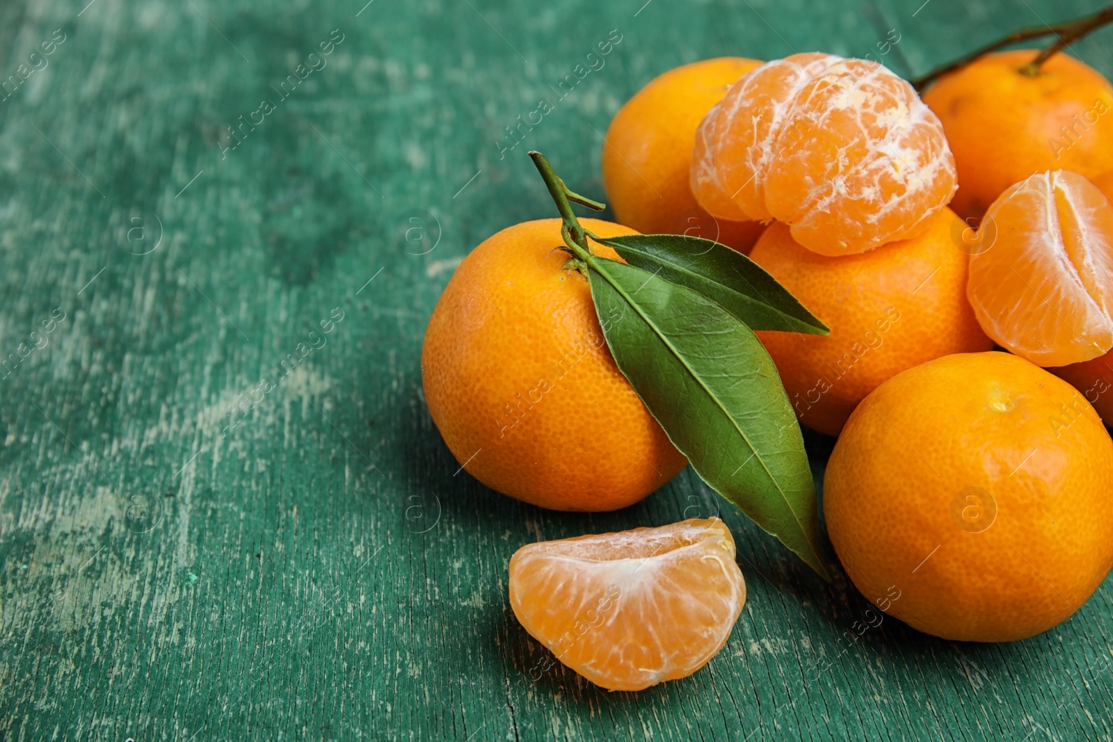 Photo of Fresh ripe tangerines with green leaves on table