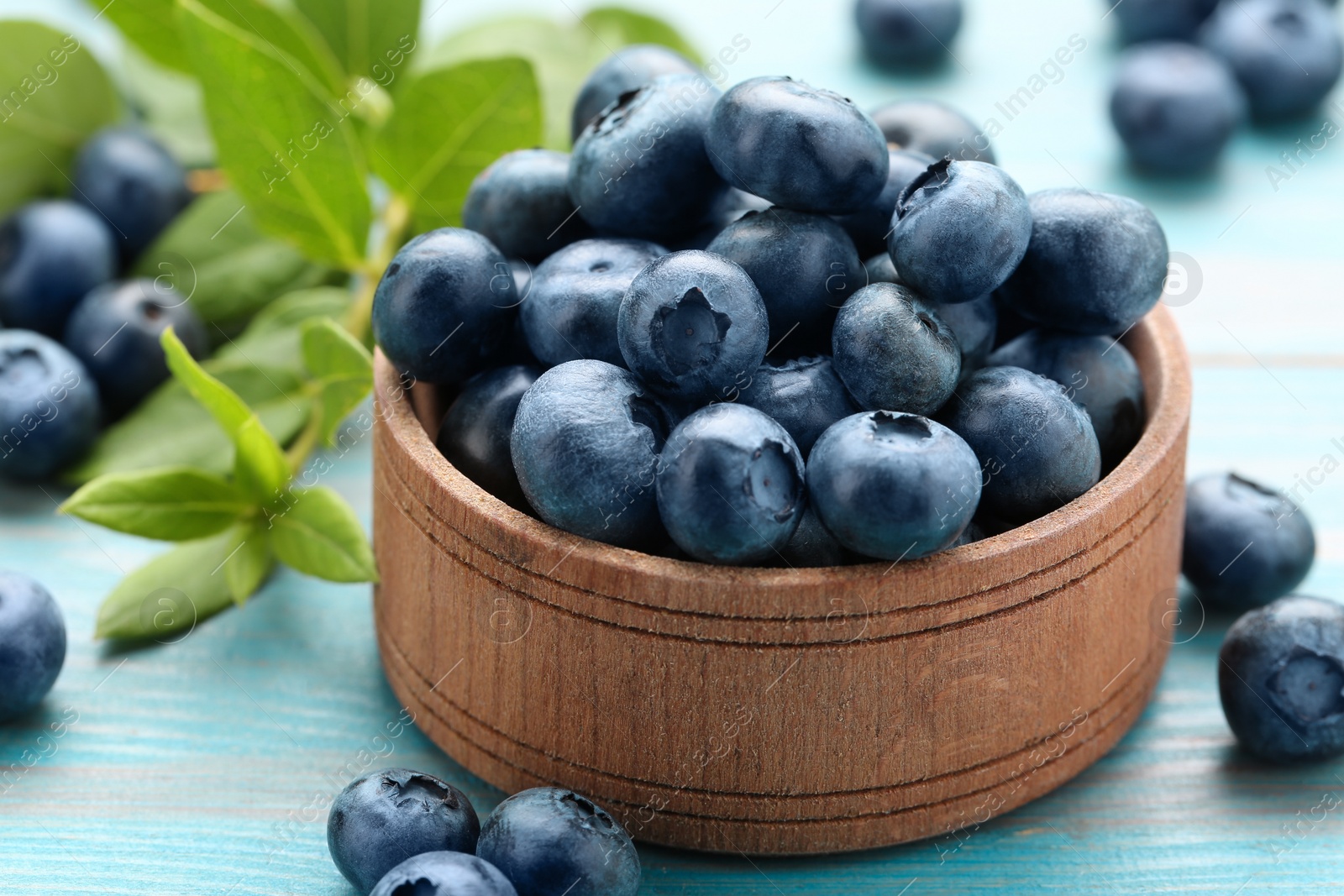 Photo of Tasty fresh blueberries on light blue table, closeup