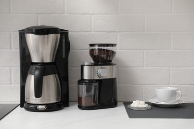 Photo of Modern coffee maker and grinder on counter in kitchen