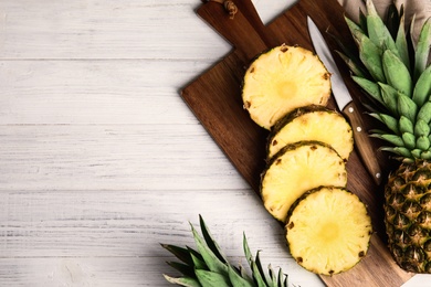 Photo of Slices of fresh pineapple on white wooden table, flat lay. Space for text