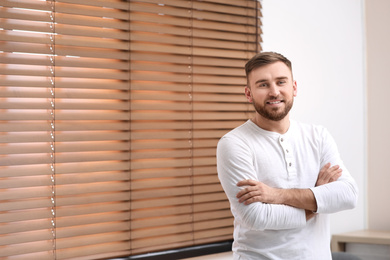 Handsome young man near window at home