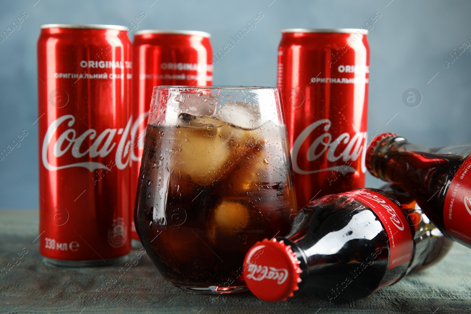 Photo of MYKOLAIV, UKRAINE - NOVEMBER 15, 2018: Bottles, glass and cans with Coca Cola on table, closeup