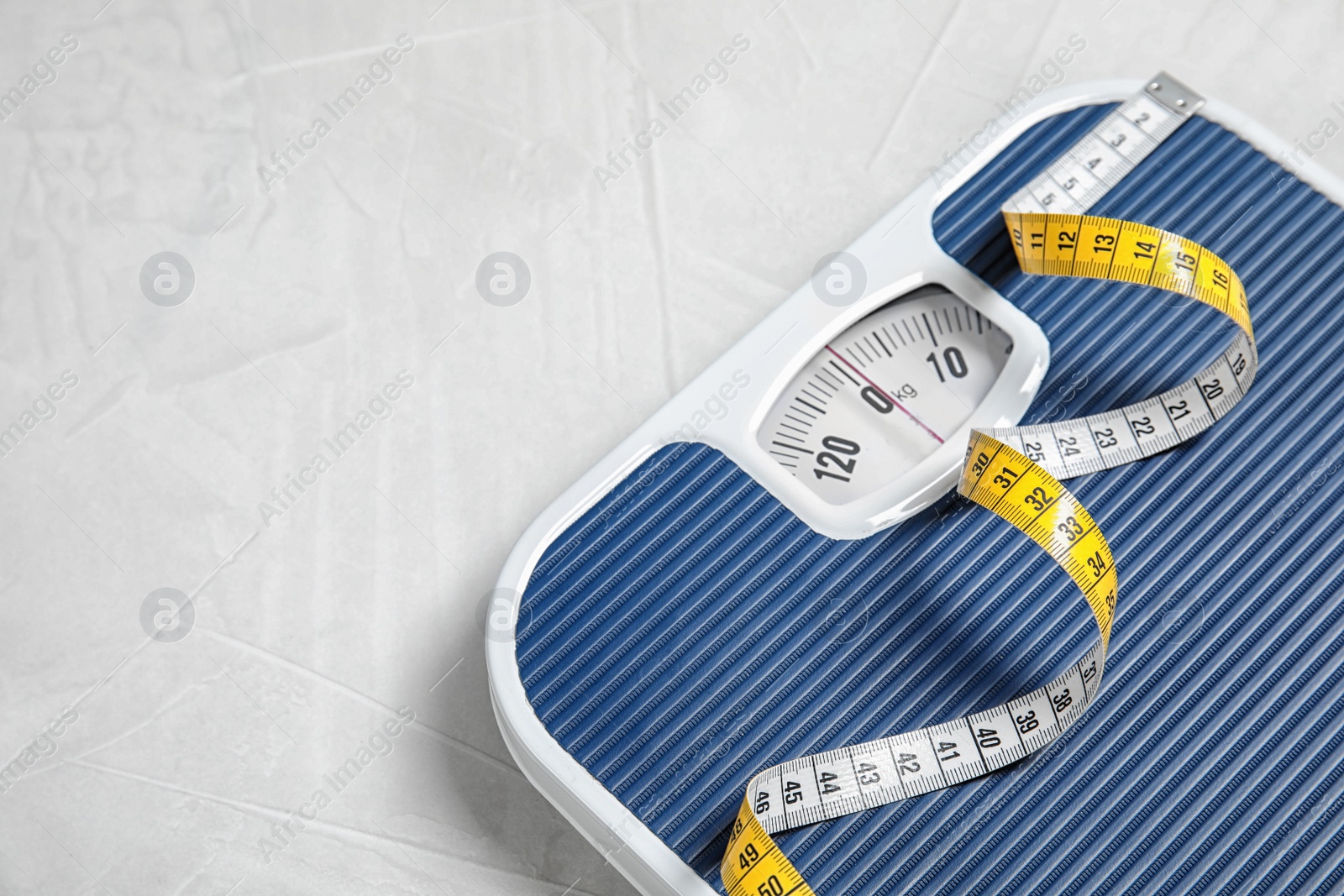 Photo of Scales and measuring tape on light background with space for text. Weight loss