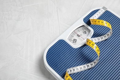 Scales and measuring tape on light background with space for text. Weight loss