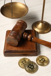 Photo of Law concept. Gavel, scales and bitcoins on white wooden table, closeup